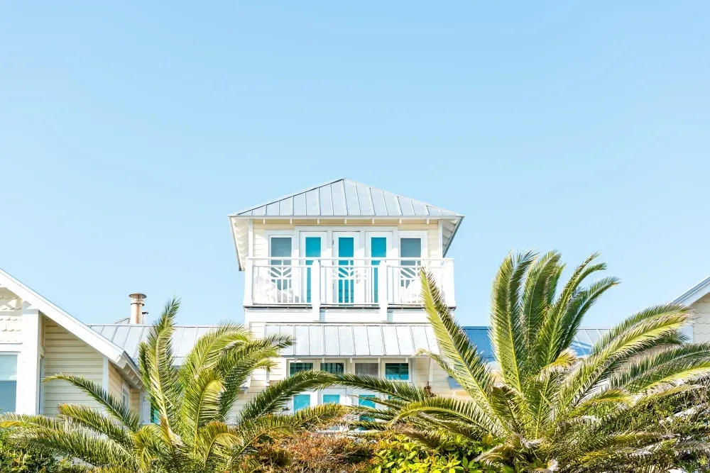 Bright vacation rental house with balconies and palm trees under a clear blue sky for 2025 rental comparisons.